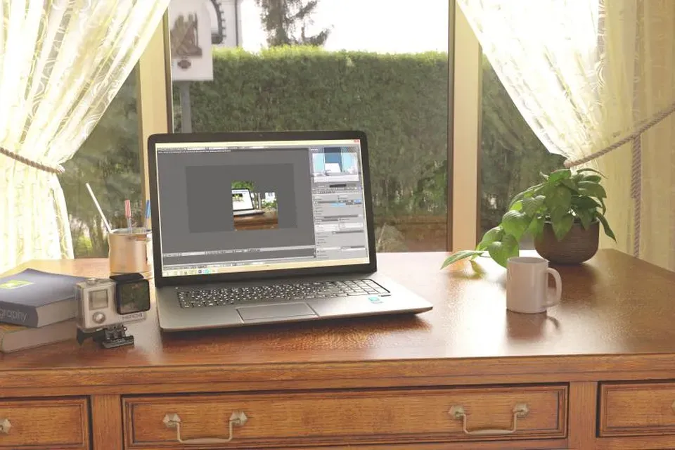 Ein aufgeräumter Arbeitsplatz mit Laptop, Mini-Server, Pflanze und einer Tasse Kaffee